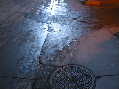 Water and light play in alley. 4th Street and 7th Avenue Southwest, Calgary. 11 February 2002. Copyright © 2002 Grant Hutchinson